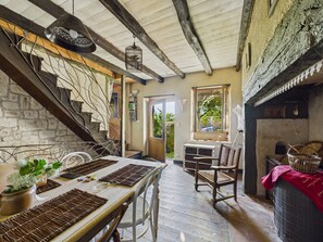 Ein rustikales Interieur mit einer Holztreppe, einem Esstisch mit Platzsets und Blick ins Freie.