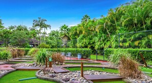 Um jardim com paisagismo, caminhos, pedras e plantas tropicais.