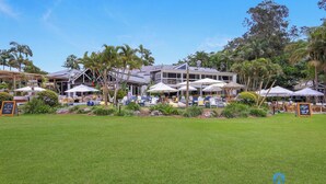 Un resort con asientos al aire libre, palmeras y un edificio con múltiples sombrillas.