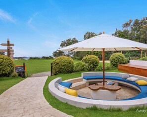 Un espacio de estar al aire libre con forma circular, que incluye una piscina, rodeado por un seto bajo y un camino.