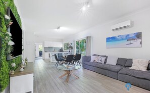Un espacio habitable moderno con comedor, cocina y un sofá gris.