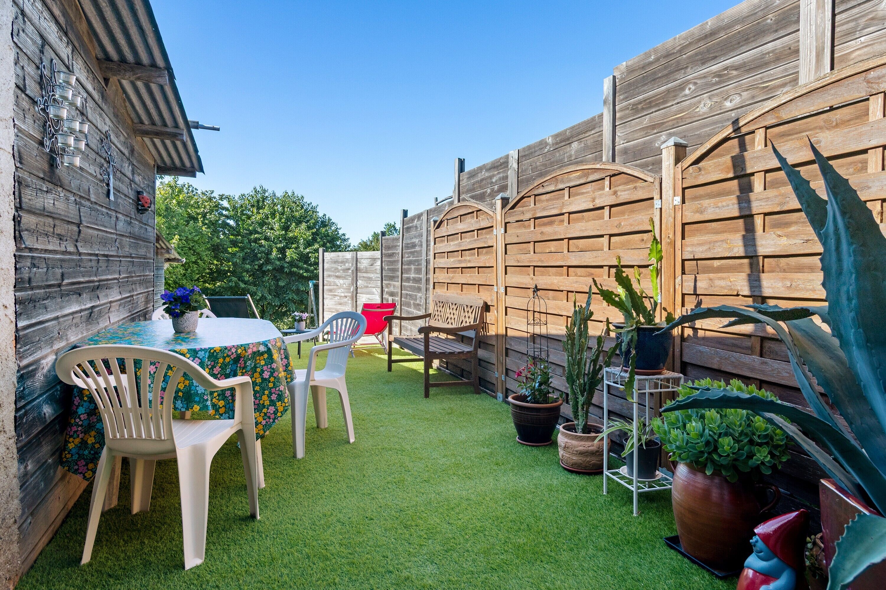 A patio with a table, chairs, and potted plants.