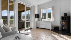 A modern, well-lit room with a fireplace, a comfortable seating area, and large windows offering a view of the outdoors. - "Rolfkarl" - 250m from the sea by Interhome (Mesinge)