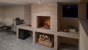 A modern living room with a built-in fireplace, a dining area with a glass table, and a kitchen area with a dishwasher.