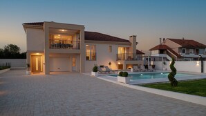 A modern two-story house with a swimming pool, outdoor seating, and a well-maintained garden.