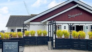 Rakennuksessa on punainen katto, ja sen kyljessä on teksti ’Dagmars’. Siinä on myös musta kyltti, jossa on kirjoitusta.