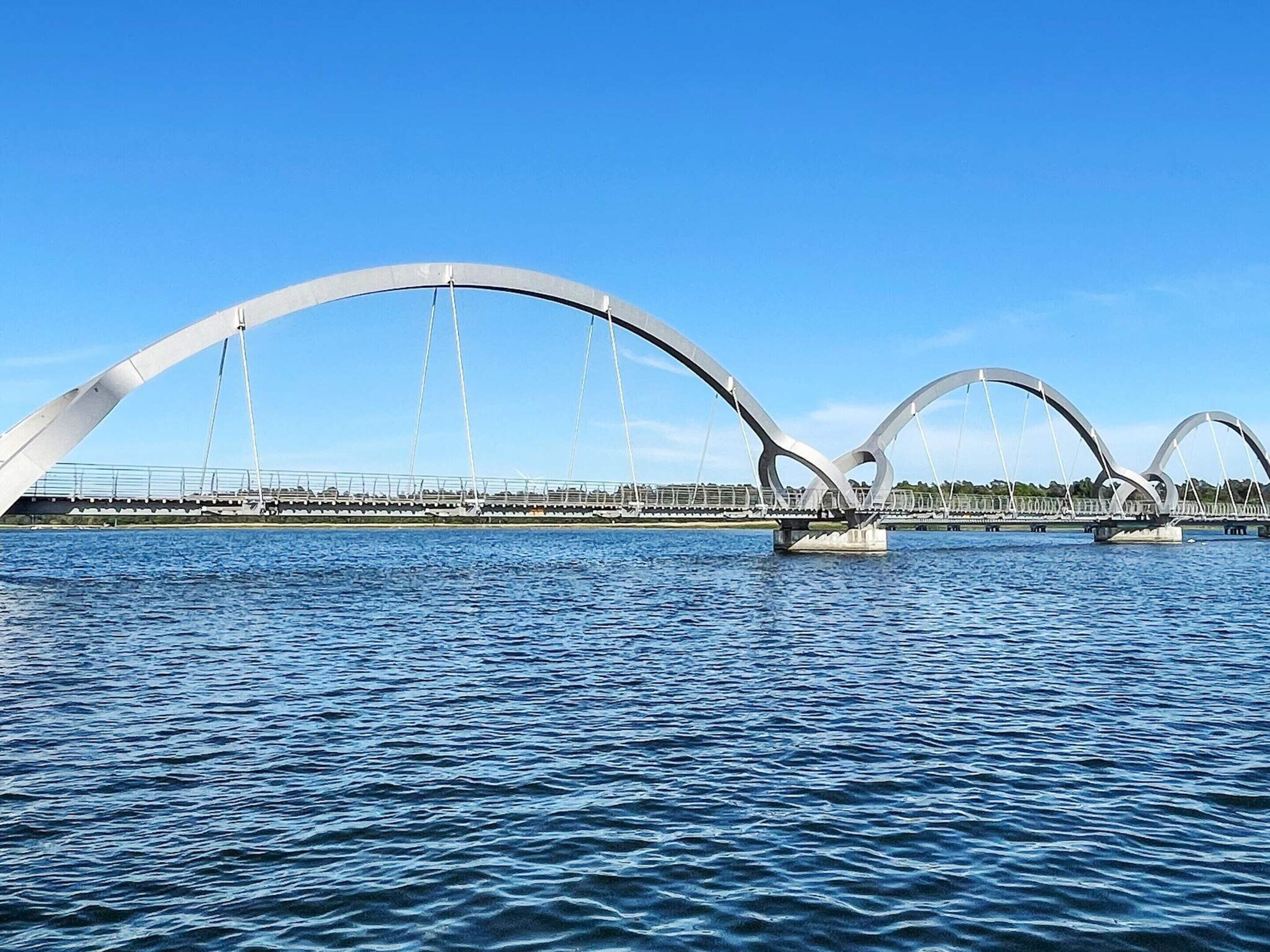 A modern bridge with a unique arch design over a body of water.