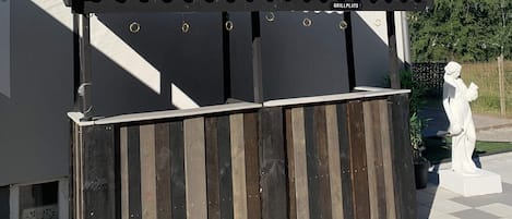 A grill area with a tiled roof and a wooden fence.