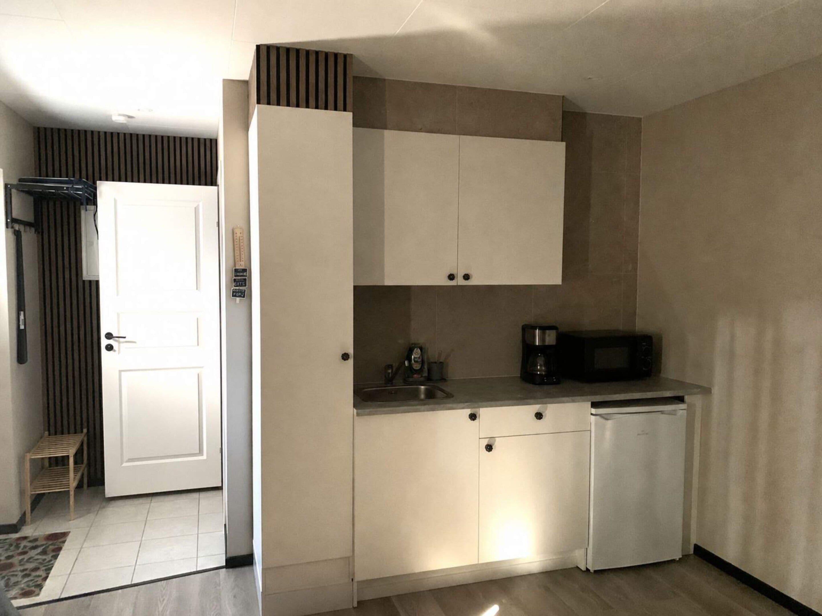 A compact kitchen with white cabinets, a microwave, and a coffee maker.