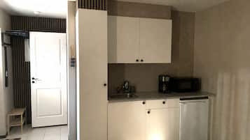 A compact kitchen with white cabinets, a microwave, and a coffee maker.