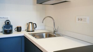 Eine moderne Küche mit Spüle aus Edelstahl, Wasserkocher und Kaffeemaschine auf der Arbeitsplatte.