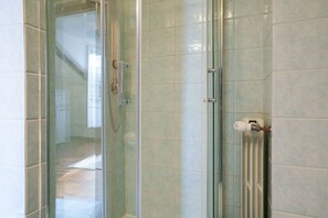 A glass-enclosed shower with a handrail, a towel rack, and a radiator. - Agostino Center Apartment (Turin)