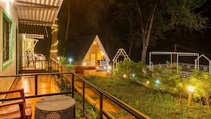 A wooden cabin with a porch, surrounded by trees and illuminated by string lights. - Dandeli Inn Resort  (Dandeli)