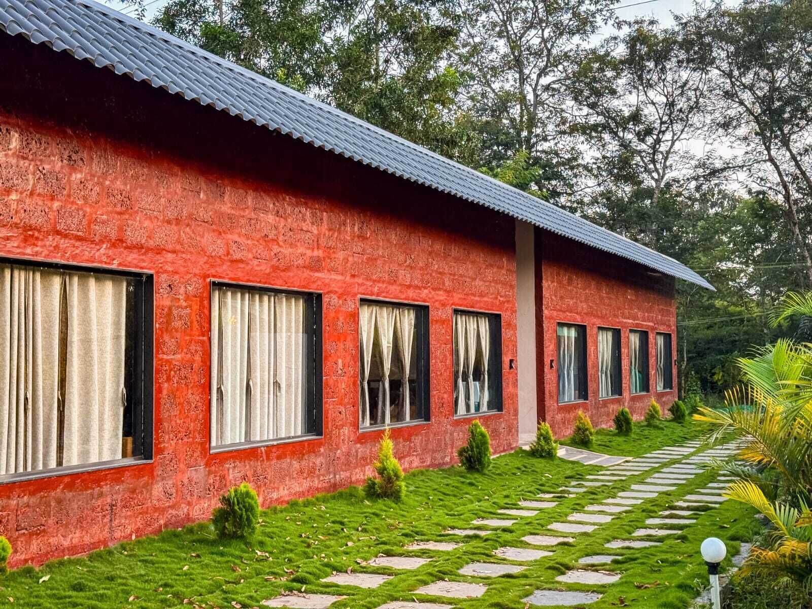 Un edificio rojo con varias ventanas y un camino que lleva a él.