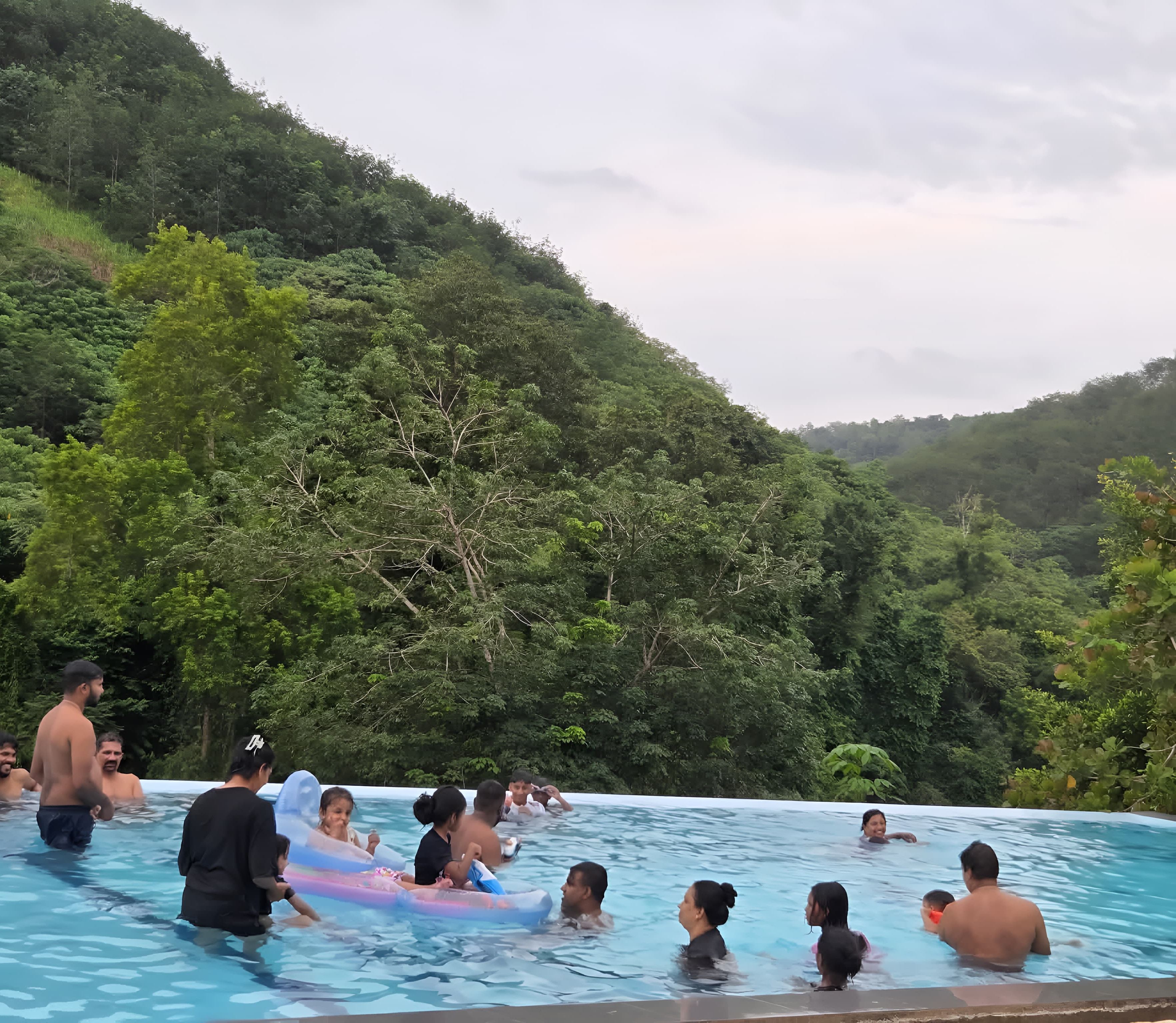 A swimming pool surrounded by lush greenery and hills.