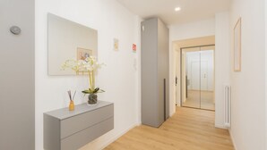 A hallway with a grey console, a mirror, a vase with flowers, a grey refrigerator, and a door leading to another room. - Milano Centro | Fontana House  (Milano)