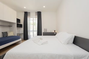 A modern hotel room with a large bed, a smaller bed, a desk, a chair, a TV, and a window with curtains.