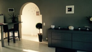 A modern kitchen with a dining area, featuring a dark grey cabinet, a potted plant, and a small table with chairs.