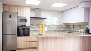 Eine moderne Küche mit Edelstahl-Kühlschrank, integriertem Mikrowellenherd, Backofen und einer Kücheninsel aus Holz mit Spüle.