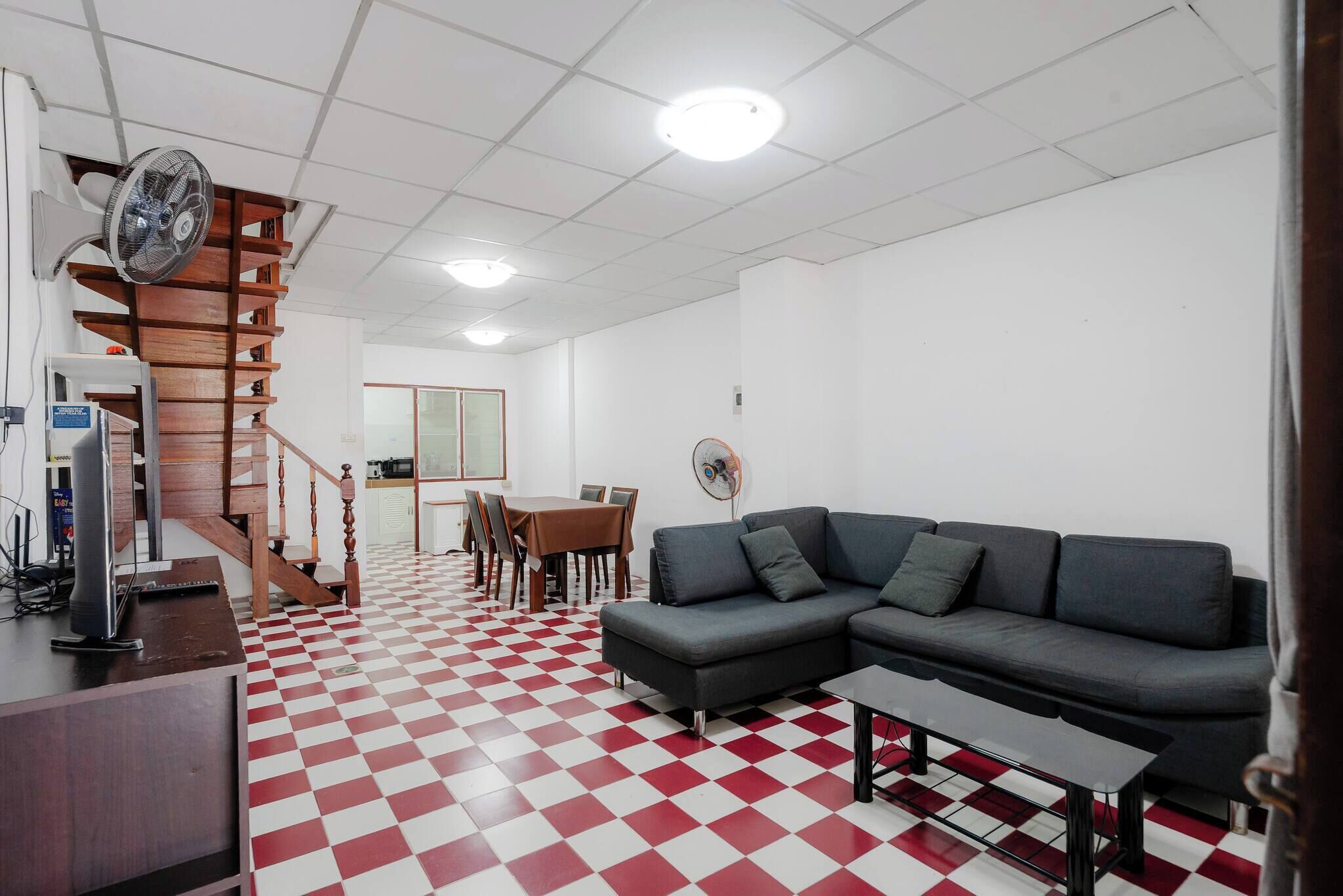 A living room with a checkered floor, a sofa, a table, and a staircase.