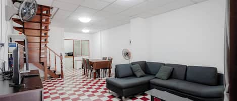 A living room with a checkered floor, a sofa, a table, and a staircase.