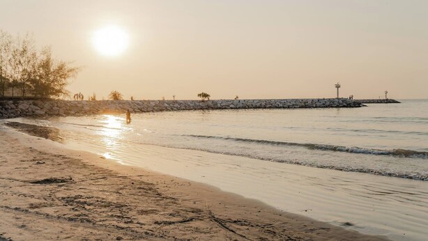 A beach with a stone wall and a pier extending into the water. - Charming 2-bedroom House in Hua Hin Soi 80,12-minute Walk to Beach (Hua Hin)