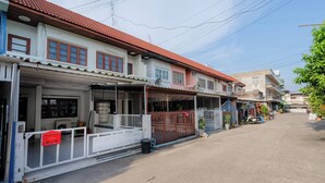 A row of two-story residential buildings with red-tiled roofs, a gated entrance, and a clear sky. - Charming 2-bedroom House in Hua Hin Soi 80,12-minute Walk to Beach (Hua Hin)