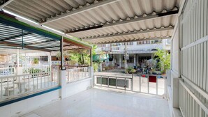 A covered outdoor area with a tiled floor, metal railings, and a view of a residential building in the background. - Charming 2-bedroom House in Hua Hin Soi 80,12-minute Walk to Beach (Hua Hin)