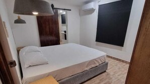 A modern bedroom with a bed, bedside table, and a large window. - Sigatoka Lodge (Sigatoka)