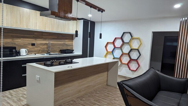A modern kitchen with a central island, a black leather chair, and a hexagonal wall decoration. - Sigatoka Lodge (Sigatoka)