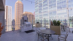Terraza en la azotea con asador, zona de estar y vistas a la ciudad.