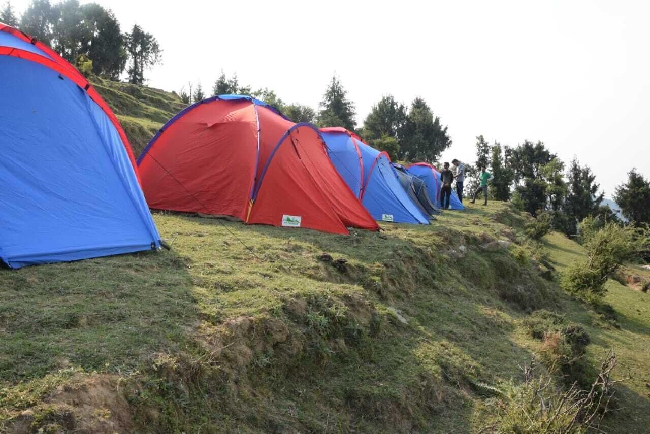 Una hilera de tiendas de campaña rojas y azules instaladas en una colina cubierta de hierba.