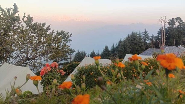 A mountainous landscape with tents and a view of the mountains in the background. - DhaulaPir Adventure (Chamba)
