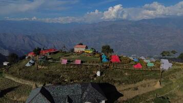 A mountainous village with several houses and a small building, surrounded by steep hills and a clear sky.