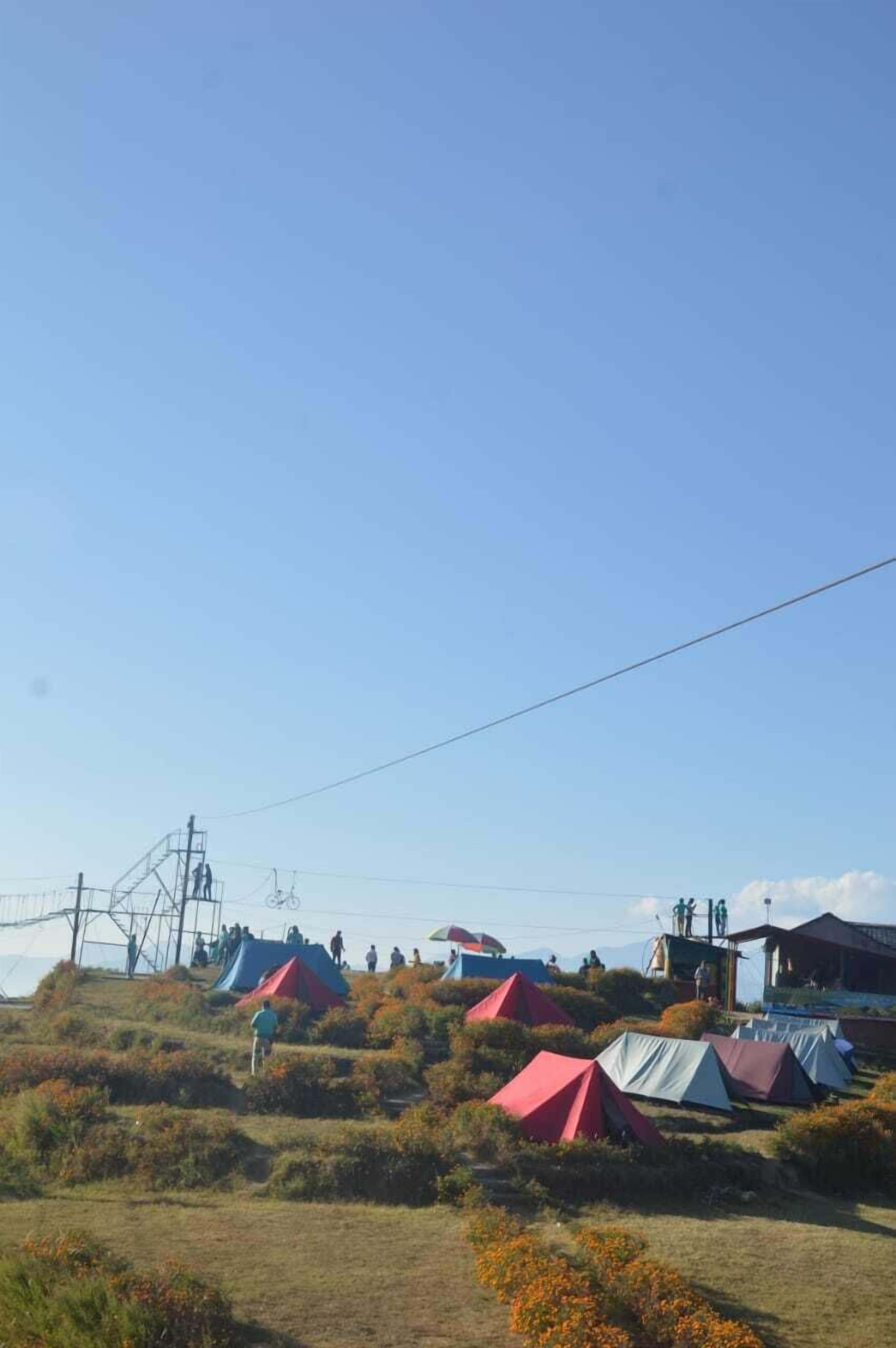 Un camping con varias tiendas de campaña y un edificio pequeño.