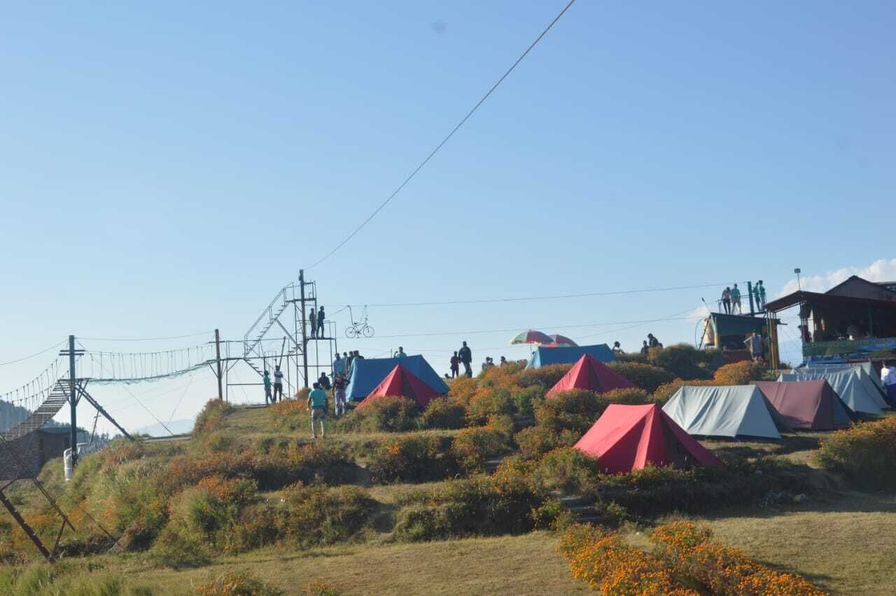 Een camping met tenten en een klein gebouw op een heuvel.