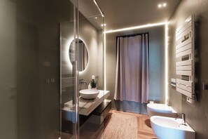 A modern bathroom with a glass-enclosed shower, a round mirror, a vanity with a marble countertop, and a separate sink. - Villa Rossa (Brunate)