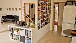A compact living space with a bookshelf, a mirror, and a refrigerator. - From November 4-6 months 80sqm apartment with roof terrace in Neukölln (Berlin)