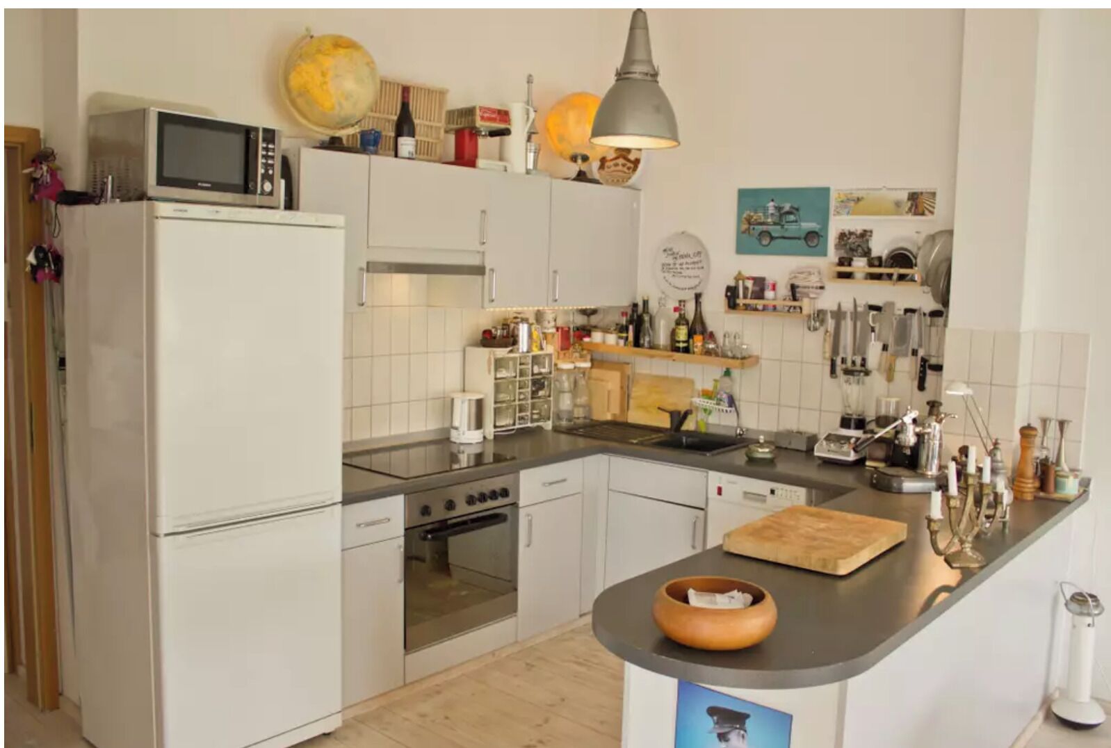 Eine moderne Küche mit weißen Schränken, einem Herd, Backofen, einer Mikrowelle sowie verschiedenen Küchengeräten und Dekorationen auf den Arbeitsflächen.