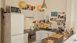 A modern kitchen with white cabinets, a stove, oven, microwave, and a variety of kitchen tools and decorations on the countertops. - From November 4-6 months 80sqm apartment with roof terrace in Neukölln (Berlin)