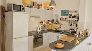 Eine moderne Küche mit weißen Schränken, einem Herd, Backofen, einer Mikrowelle sowie verschiedenen Küchengeräten und Dekorationen auf den Arbeitsflächen.