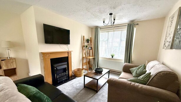 Ein Wohnzimmer mit Kamin, Sofas, einem Couchtisch und einem Fernseher.