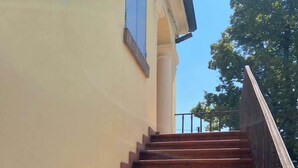 A set of outdoor wooden stairs leading up to a building with a yellow wall and a black railing. - B e B Villa Livia (Rolo)