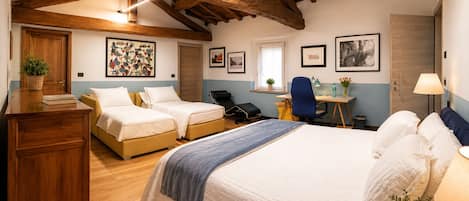 A bedroom with two single beds, a desk, a chair, and a lamp.