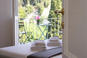 A balcony with a view of a mountainous landscape, a small table with a potted plant, and neatly folded towels on a bed. - Rental in Rome Flaminia View Apartment (Rome)