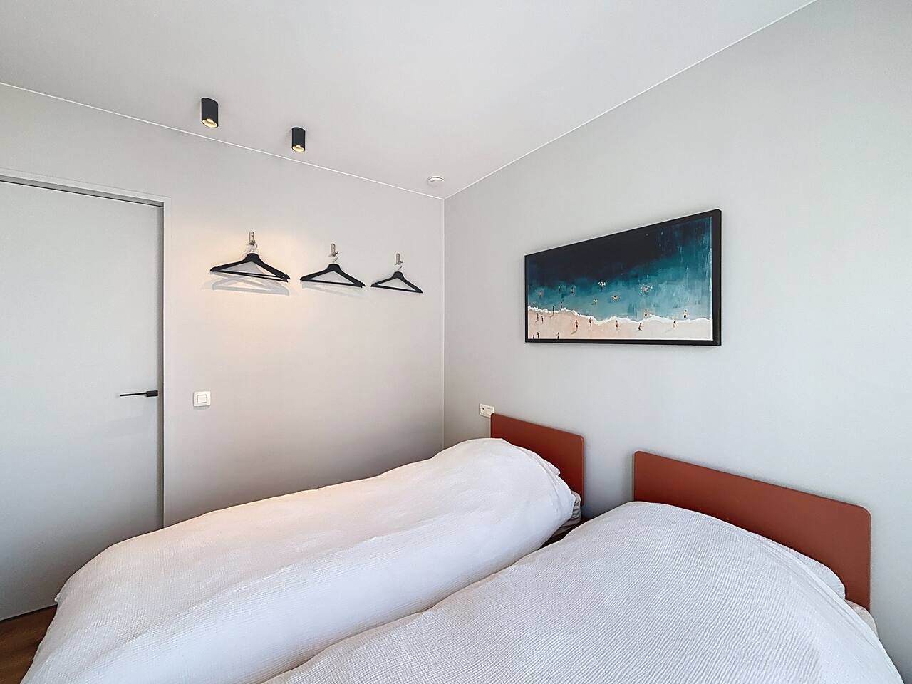 Une chambre à coucher avec un lit, une porte et une œuvre d’art accrochée au mur.