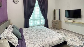 Una camera da letto con un letto, una televisione, una cassettiera, una sveglia e un condizionatore d'aria.