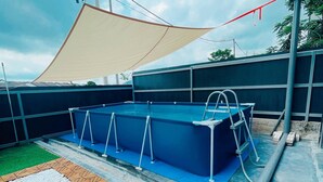 Una piscina sul tetto con bordo blu, circondata da una tenda beige e un pavimento a motivi geometrici.