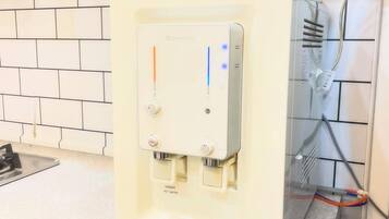 Un dispensador de agua con panel de control, una etiqueta de advertencia de seguridad y una bandeja metálica.