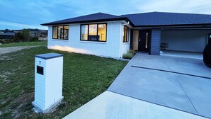 A modern single-story house with a garage, a well-maintained lawn, and a mailbox. - 7th Heaven in Rotorua (Rotorua)
